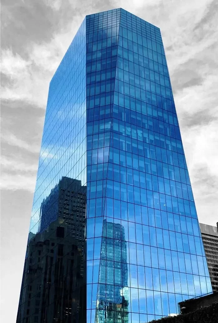 The blue, reflective, rectilinear facade of 535 Mission Street shown against a black and white, cloudy San Francisco sky.