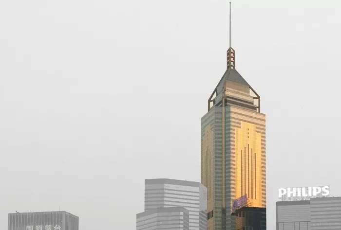 The Central Plaza high-rise picked out in colored sunlight of a Hong Kong sky set against a black & white background.