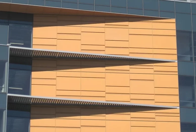 A close up of the orange and gray metal facade of Golden State Warriors & One Hotel Residential in Mission Bay, CA.