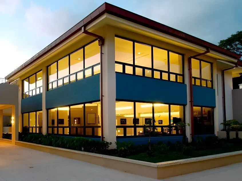 A corner view of the Case Middle School in Honolulu, with a dark blue sky and internally lit facade.