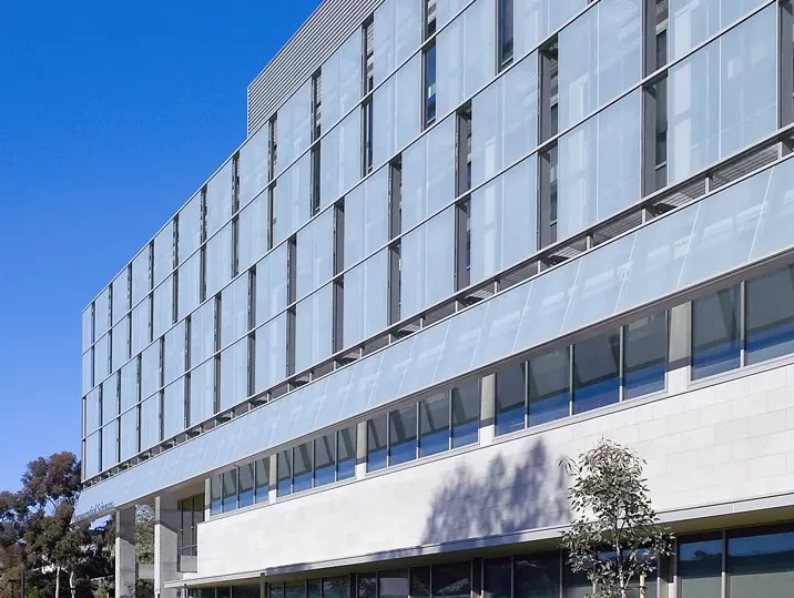 The external glass facade shades on the Skaggs School of Pharmacy at UC San Diego against a right blue sky.