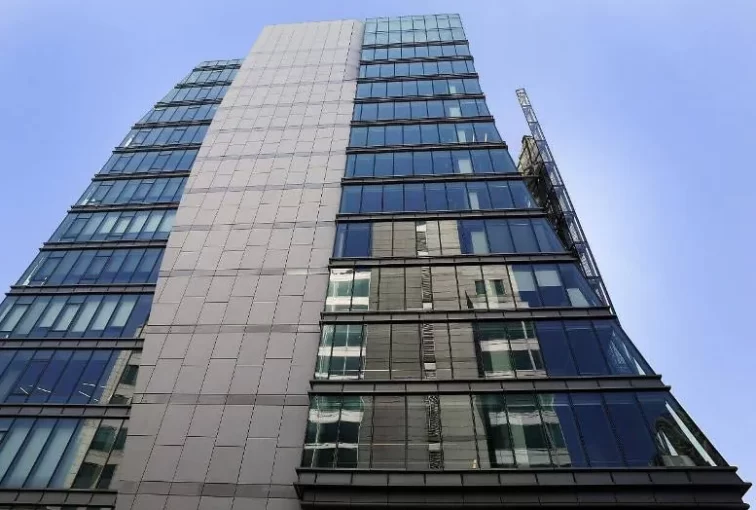 A ground level, upwards view of the blue and gray facade of the San Francisco Public Utilities Commission HQ, a high-rise building in San Francisco, CA.