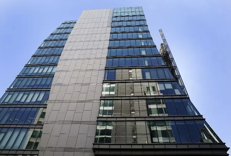 A ground level, upwards view of the blue and gray facade of the San Francisco Public Utilities Commission HQ, a high-rise building in San Francisco, CA.