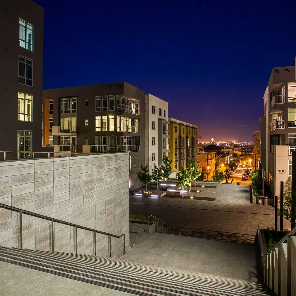 The Alta Laguna Multifamily Housing development showing pastel colored facades punched with windows and small balconies, all set against a dark blue & purple San Francisco night sky.