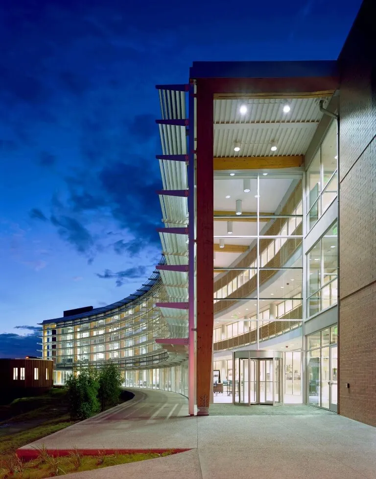 End view of the interior-lit facade the Applied R&D Building at Northern Arizona University, showing the curved shading system set against a dark blue night sky.