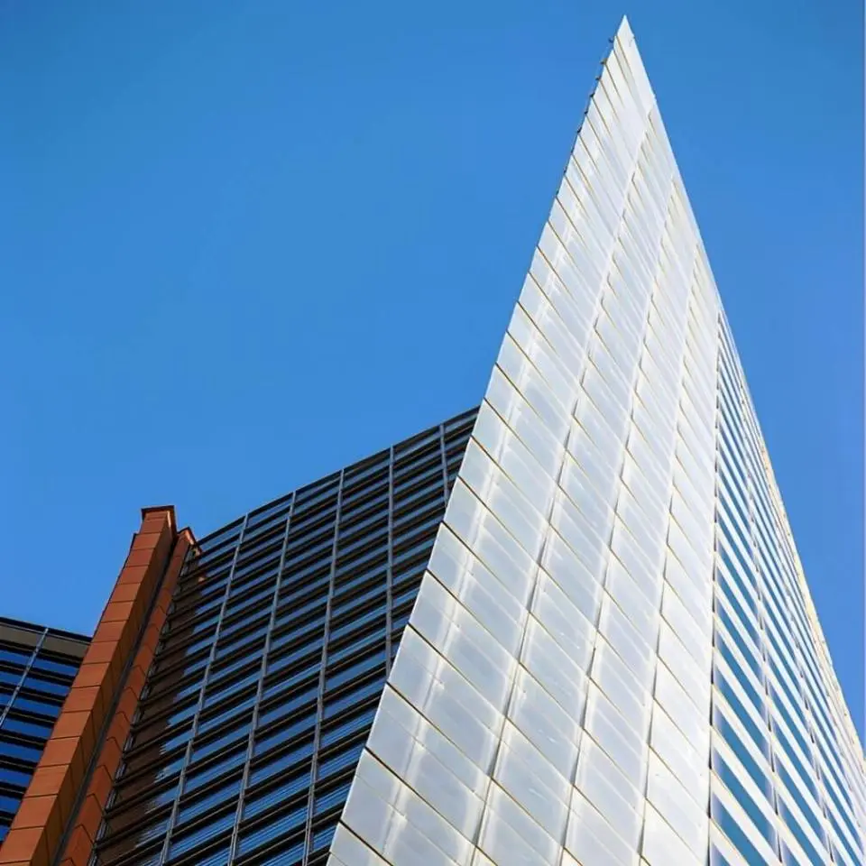 The red brick, grey metal and dark glass of the twisted high-rise facade of Aurora Place in Sydney, Australia.