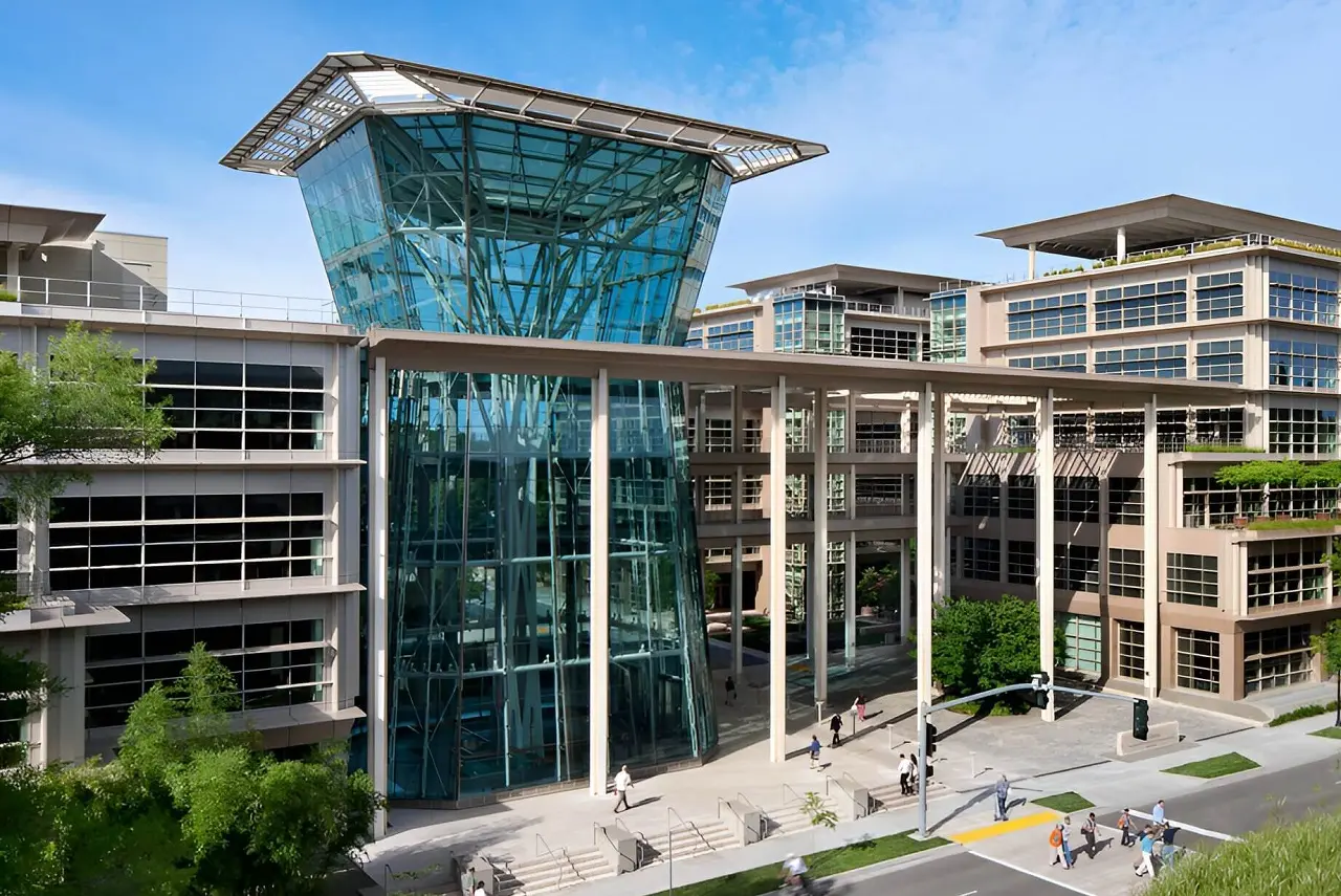 The white concrete, steel and green glass facade of the CalPERS HQ Complex under a bright blue sky.