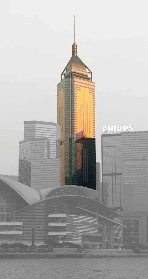 The Central Plaza high-rise picked out in golden sunlight in Hong Kong sky set against a black & white background.