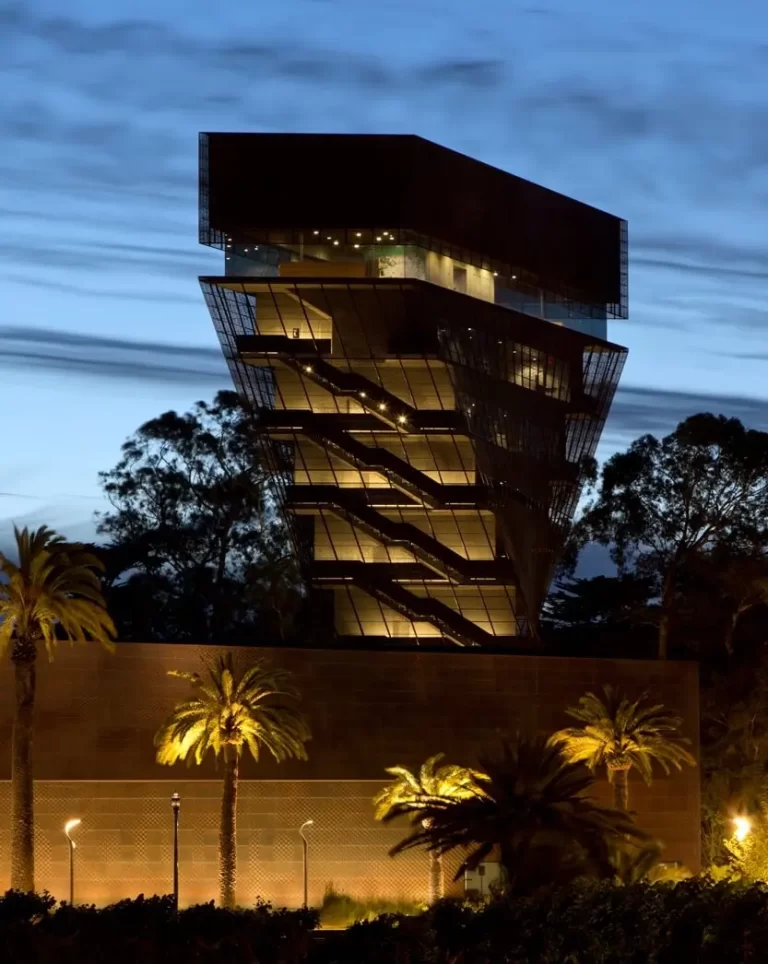 Sunset view of the twisted metal tower of the de Young Museum set against cloud-streaked sky.