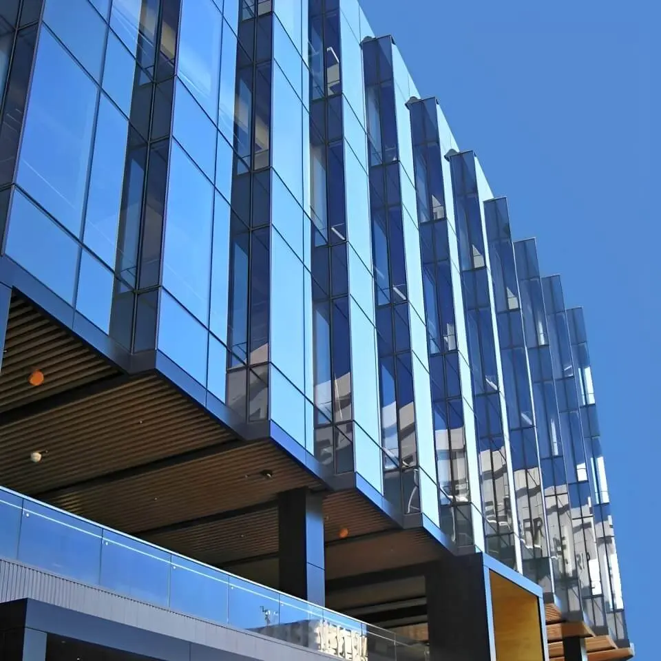 The sawtooth glass facade of Mission Bay Golden State Warriors Chase Center Towers set against a bright blue sky.