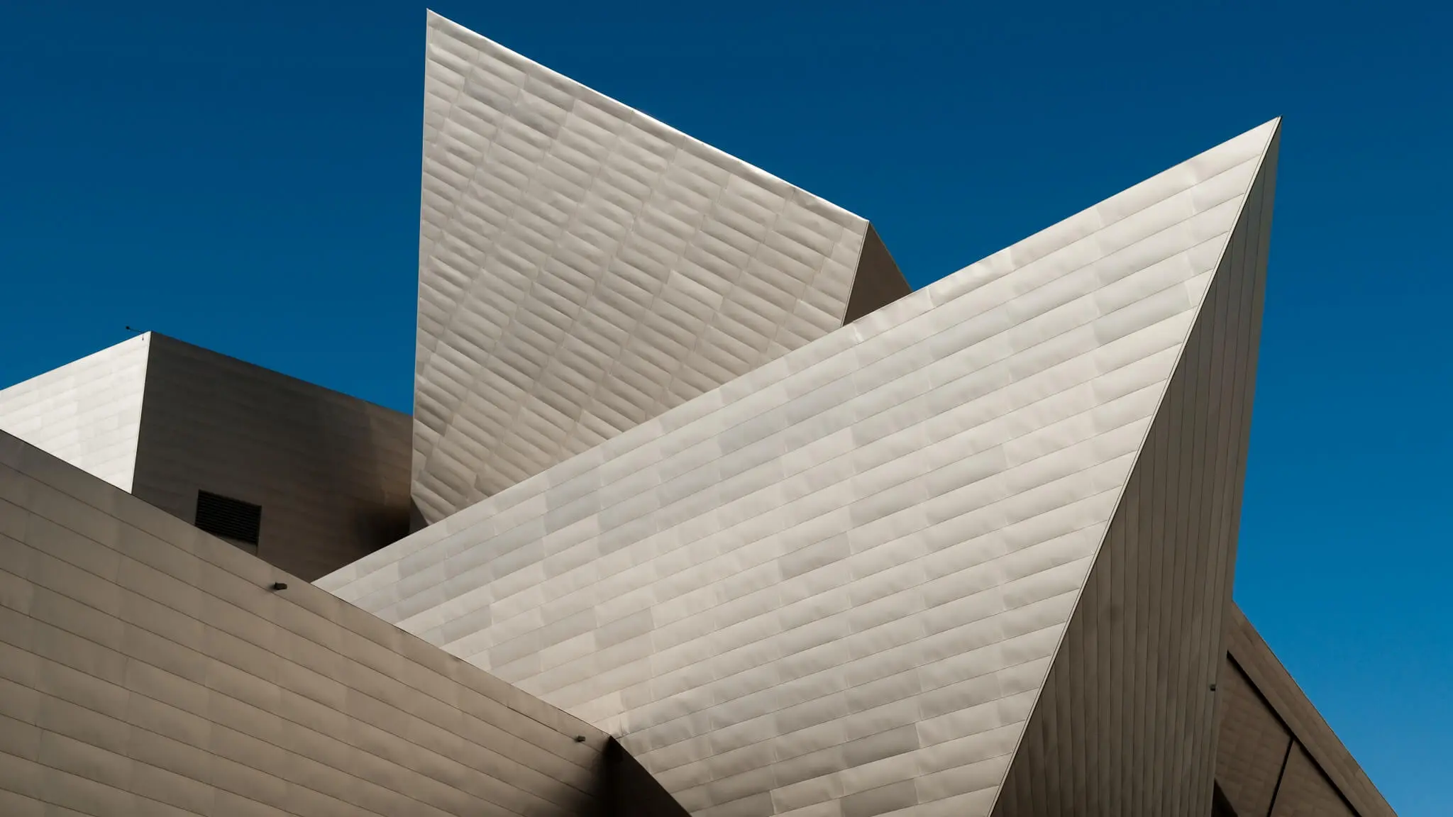 The white angular facade faces of the Denver Art Musuem set against a bright blue Colorado sky.
