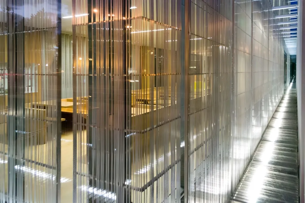 The interior of the cavity of the double-skin facade of the Jaqua Center for Student Athletes at the University of Oregon, illuminated by interior lighting.