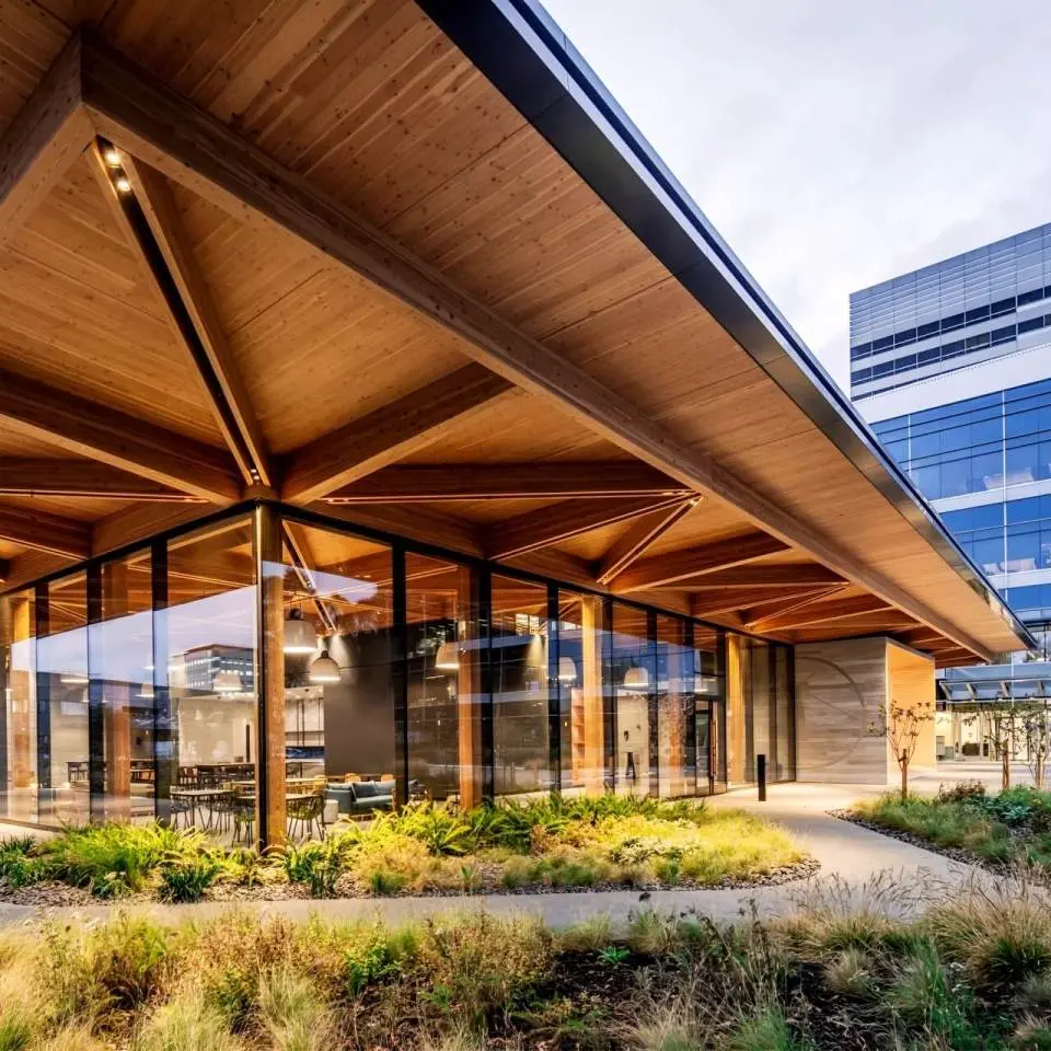 The clear glass facade and deep timber roof overhangs of the Lighthouse building.