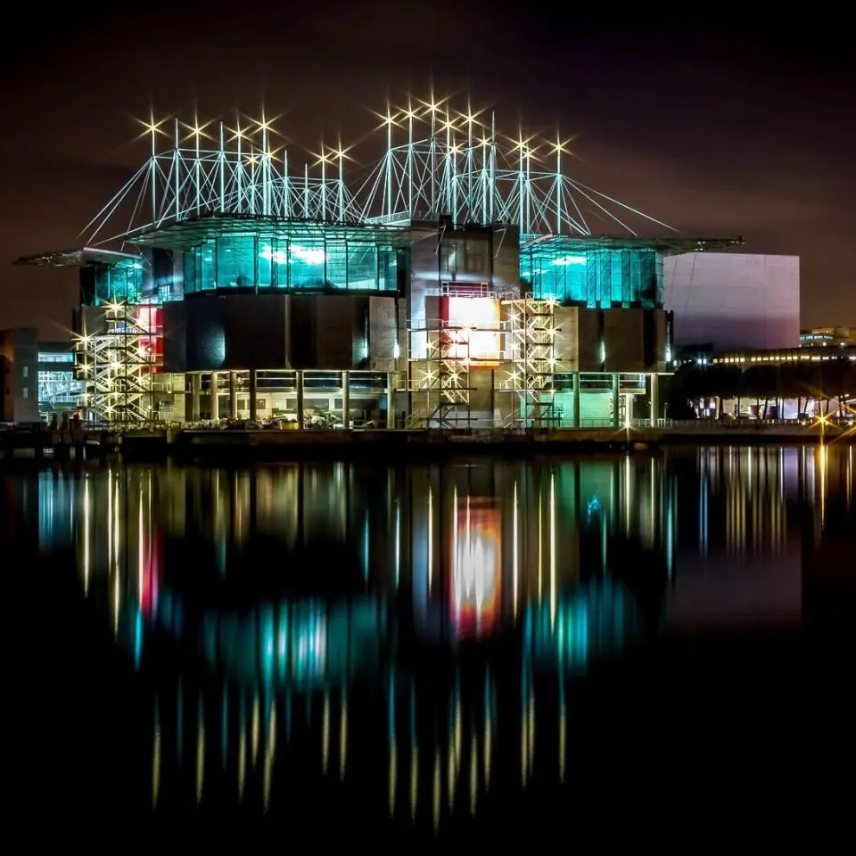 The illuminated facade of the Lisbon Aquarium reflected in the dark ocean.