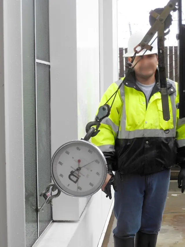 A winch and scale being used to stress test a bolt in a maintenance access tie-back bolt pull-out test.