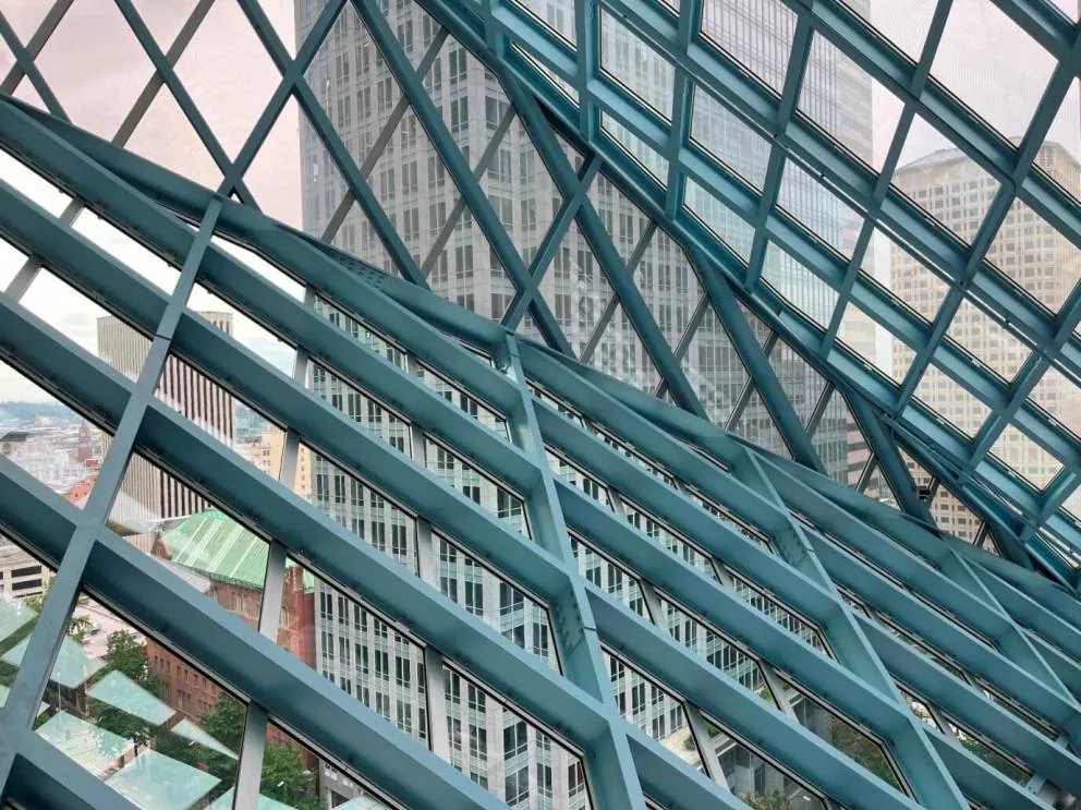 Close up interior view through the gray steel lozenges of the facade of the Seattle Central Library, showing the city below.