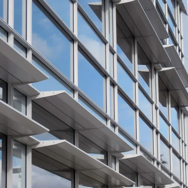 Close-up of the gray metal horizontal shading devices on the glass facade, reflecting in the cloudy blue sky at the Valley Specialty at Santa Clara Valley Medical Center.