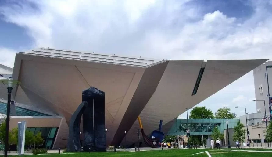 The cream angular facade faces of the Denver Art Museum set against a cloudy blue Colorado sky.
