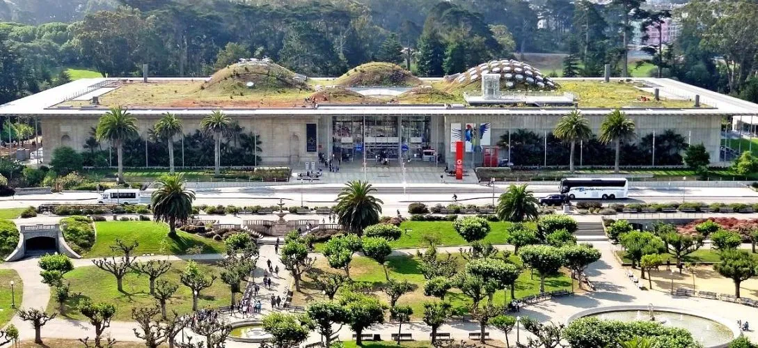 Panoramic view of the California Academy of Sciences building in Golden Gate Park showing the curvilinear grass roof with deep photovoltaic overhangs.