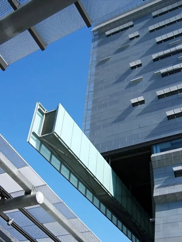 Ground-up view of a corner of the green and gray facade of the Caltrans District 7 HQ building set against a bright blue California sky.