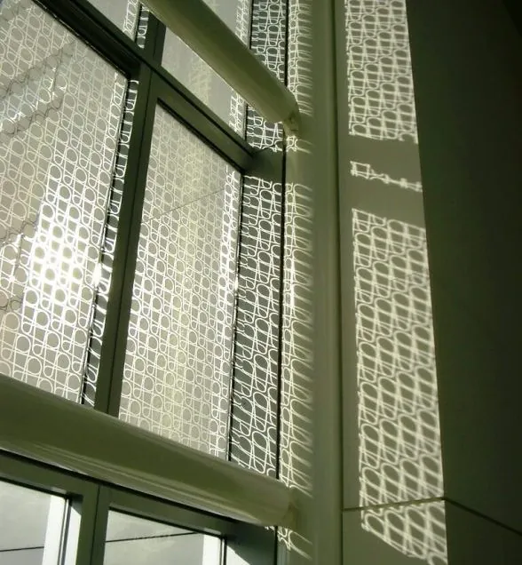 The white frit patterns of the glass facade of Moscone Convention Center West casting curved shadows on the interior support structure and walls.