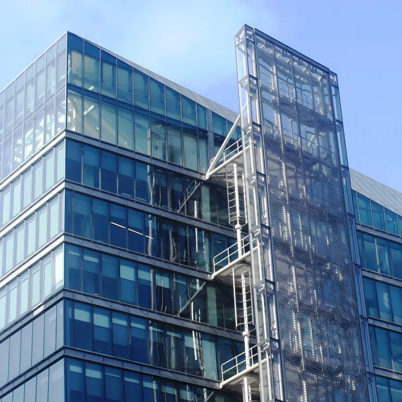 A ground level, upwards view of the blue and gray facade of the San Francisco Public Utilities Commission HQ, a high-rise building in San Francisco, CA.